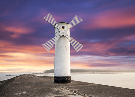 Lighthouse windmill with dramatic sunset sky, Swinoujscie, Baltic Sea, Poland の写真素材