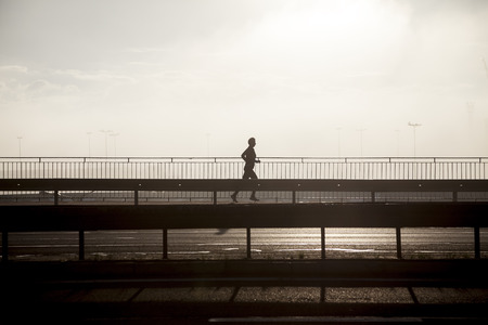 Silhouette of running man on the highway at sunrise  の写真素材