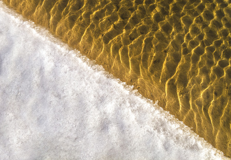 Picture with yellow sand and waves in shallow water  の写真素材