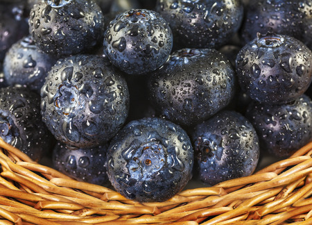 Fresh blueberries with water drops in wicker basket.の写真素材