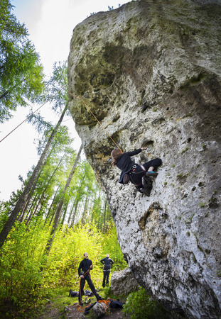 Young woman climbing difficult rock in forest.の写真素材