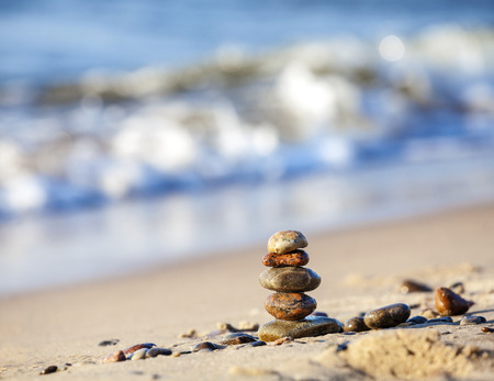 Stones pyramid on sand symbolizing zen, harmony, balance, blue ocean in the background   の写真素材