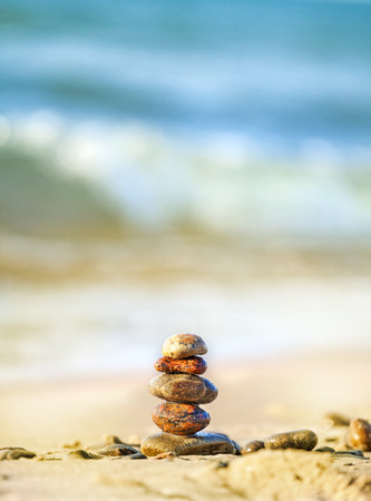 Stones pyramid on sand symbolizing peace and harmony, blue ocean in the background   の写真素材