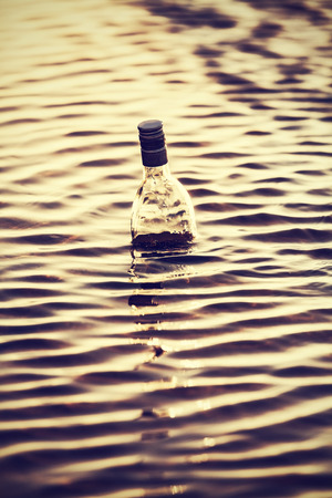 Bottle in water at sunset の写真素材