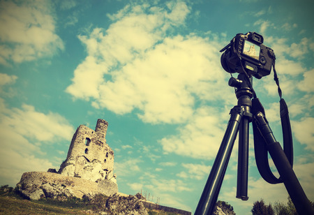 Camera on tripod with summer landscape with ruins, vintage retro style  の写真素材