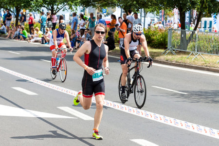 SZCZECIN, POLAND - JULY 06, 2014  Runner and cyclists during first Triathlon Szczecin race のeditorial素材