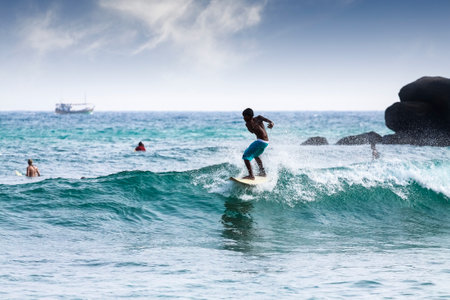 Mirissa, Sri Lanka - March 04, 2009  Silhouette young boy surfing on waves on famous beach in Sri Lanka  This area is best known for its massive waves, attracting surfers from all over the world のeditorial素材