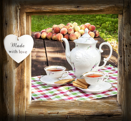 Tea set in garden in wooden frame with heart.の写真素材