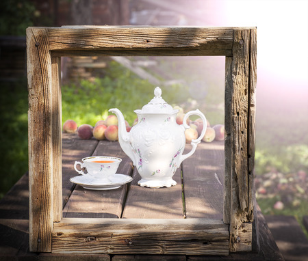 Vintage picture of tea set in garden in wooden frame.の写真素材
