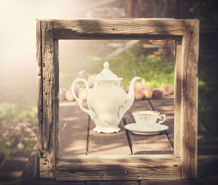 Vintage picture of tea set in garden in wooden frame.の写真素材