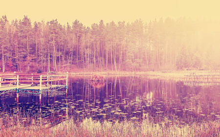 Vintage filtered picture of wooden lake pier at sunset.の写真素材