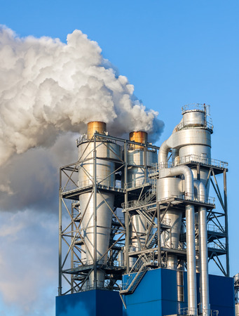 Smoke clouds from a chimney against blue sky.の写真素材