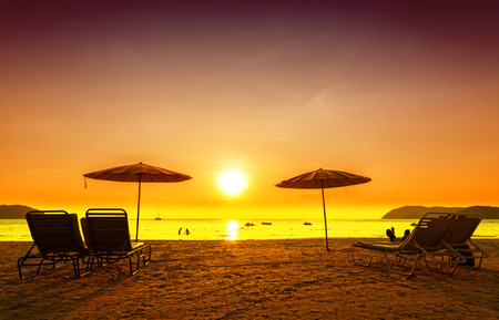 Retro filtered picture of beach chairs and umbrellas on sand at sunset. Concept for rest, relaxation, holidays.の写真素材