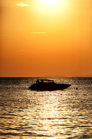 Silhouette of a motor speed boat at sunset.の写真素材