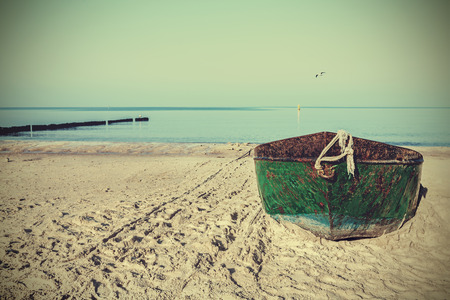 Retro filtered picture of an old rusty steel boat on the beach.の写真素材