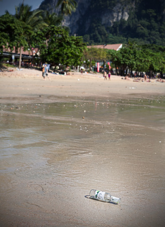 Empty bottle on a beach, tourism and environment concept, shallow depth of field.の写真素材