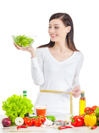 Young happy woman with salad, measuring her waistline. Healthy food ans lifestyle concept.の写真素材