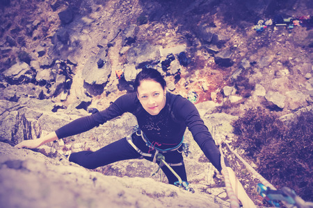 Vintage style filtered picture of a young woman climbing wall.の写真素材
