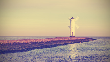 Retro vintage stylized sunrise over Baltic Sea coast, lighthouse in Swinoujscie, Poland.の写真素材