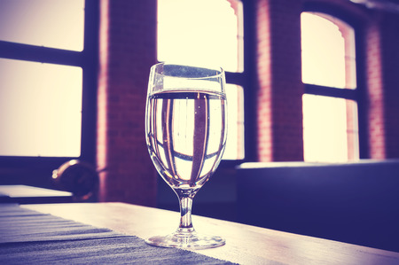 Vintage toned glass of water on a table.の写真素材