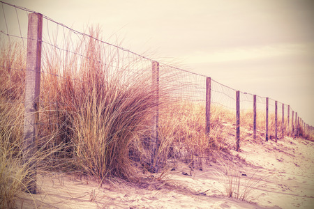 Vintage retro filtered photo of fence on a dune, nature background.の写真素材