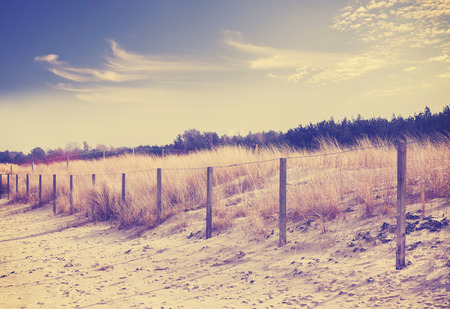 Vintage retro filtered photo of fence on dune, nature background.の写真素材