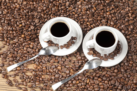 Two espressos among coffee beans on a wooden table.の写真素材