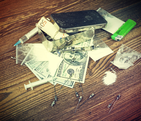 Vintage toned photo of drugs, money, needles and syringes on a wooden background.の写真素材