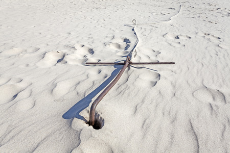 Rusty boat anchor in the sand on the beach.の写真素材