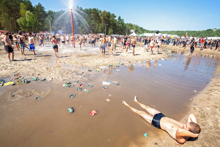 Kostrzyn nad Odra, Poland - August 1, 2015: Young man resting at the mud pool during 21th Woodstock Festival Poland (Przystanek Woodstock), one of the biggest open air festivals in Europe.のeditorial素材