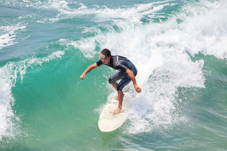 Venice, Los Angeles, USA - August 22, 2015: Man riding wave at Venice Beach on a beautiful sunny day.のeditorial素材