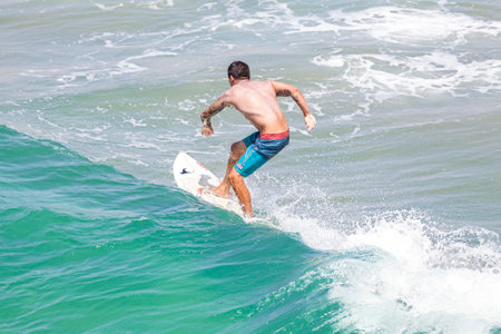 Venice, Los Angeles, USA - August 22, 2015: Man riding wave at Venice Beach on a beautiful sunny day.のeditorial素材
