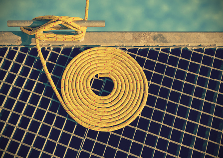 Retro toned marine background made of mooring rope with a cleat on a pier.の写真素材
