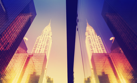 Vintage style Manhattan skyscrapers at sunset reflected in windows, NYC, USA.の写真素材
