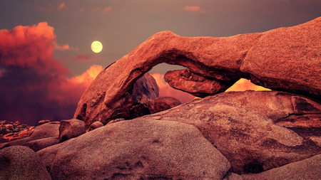 Purple sunset and rising moon over arch in Joshua Tree National Park, California, USA.の写真素材