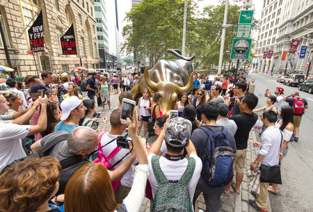 New York, USA - August 16, 2015: Tourists taking pictures of the Charging Bull in Bowling Green Park, Financial District in Manhattan.のeditorial素材