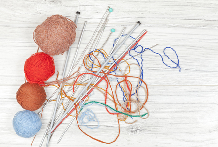 Tangled threads with yarn balls and needles on wooden board, concept background with space for text.の写真素材