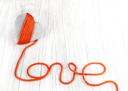 Wooden heart with red yarn love sign, space for text.の写真素材