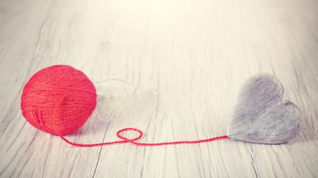 Wooden heart connected to red yarn, concept picture.の写真素材