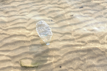 Plastic bottle in shallow sea water, environmental pollution concept.の写真素材