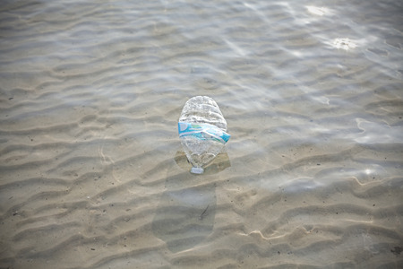 Plastic bottle in shallow sea water, environmental pollution concept.の写真素材