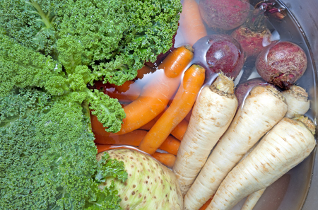 Dirty vegetables in a kitchen sink filled with water.の写真素材