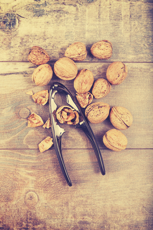 Vintage stylized walnuts and nutcracker on wooden background, space for text.の写真素材