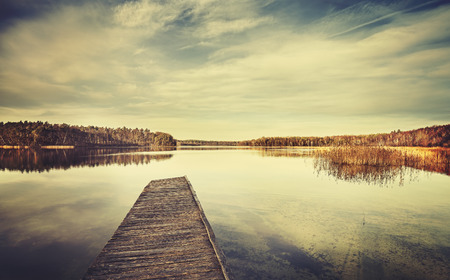 Vintage stylized picture of a lake and wooden pier.の写真素材