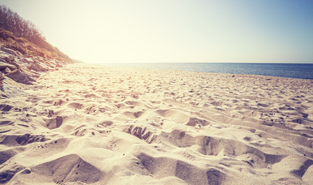 Vintage toned beach at sunset, focus on sand.の写真素材