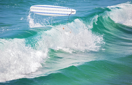 Surfer legs in water and surfing board in the air after falling a wave.