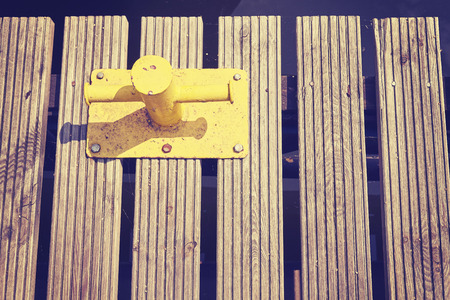 Vintage toned old yellow mooring bollard on wooden pier.の写真素材