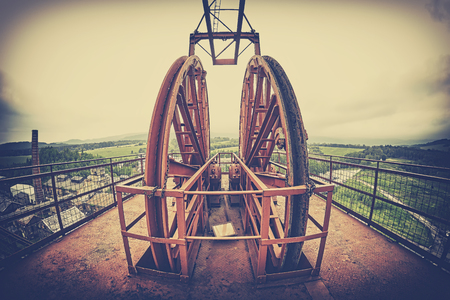 Vintage stylized fisheye lens photo of a mine shaft pulley wheel. Industrial detail background.の写真素材
