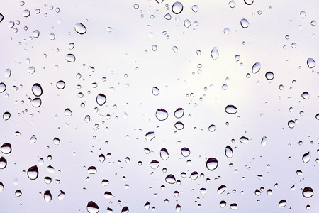 Retro toned photo of raindrops on a dusty glass.