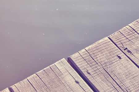 Vintage toned close up photo of an old wooden pier by a lake, background with space for text.の写真素材